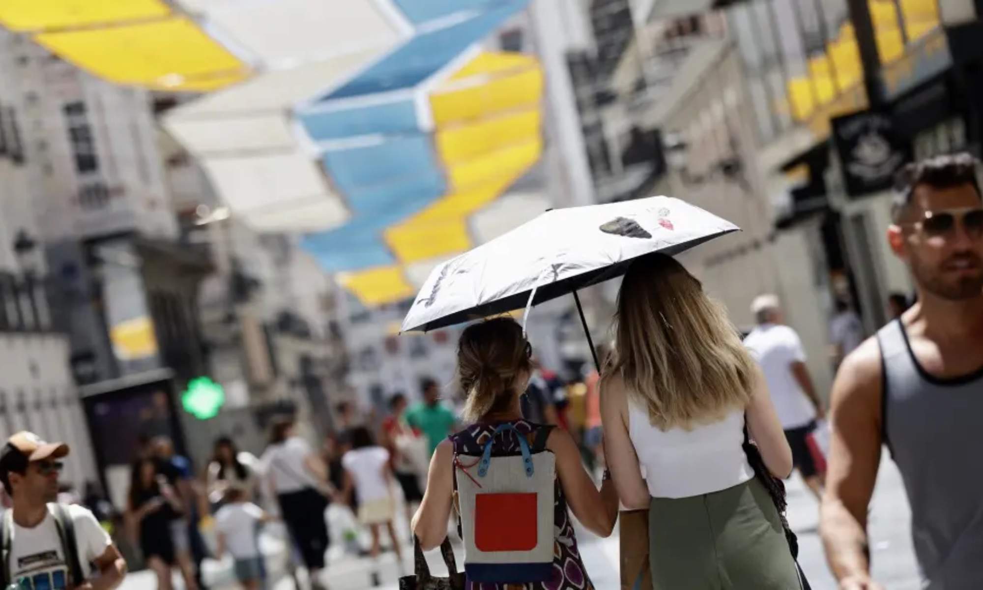 Varias personas se protegen, con paraguas,  del calor en el centro de Madrid.