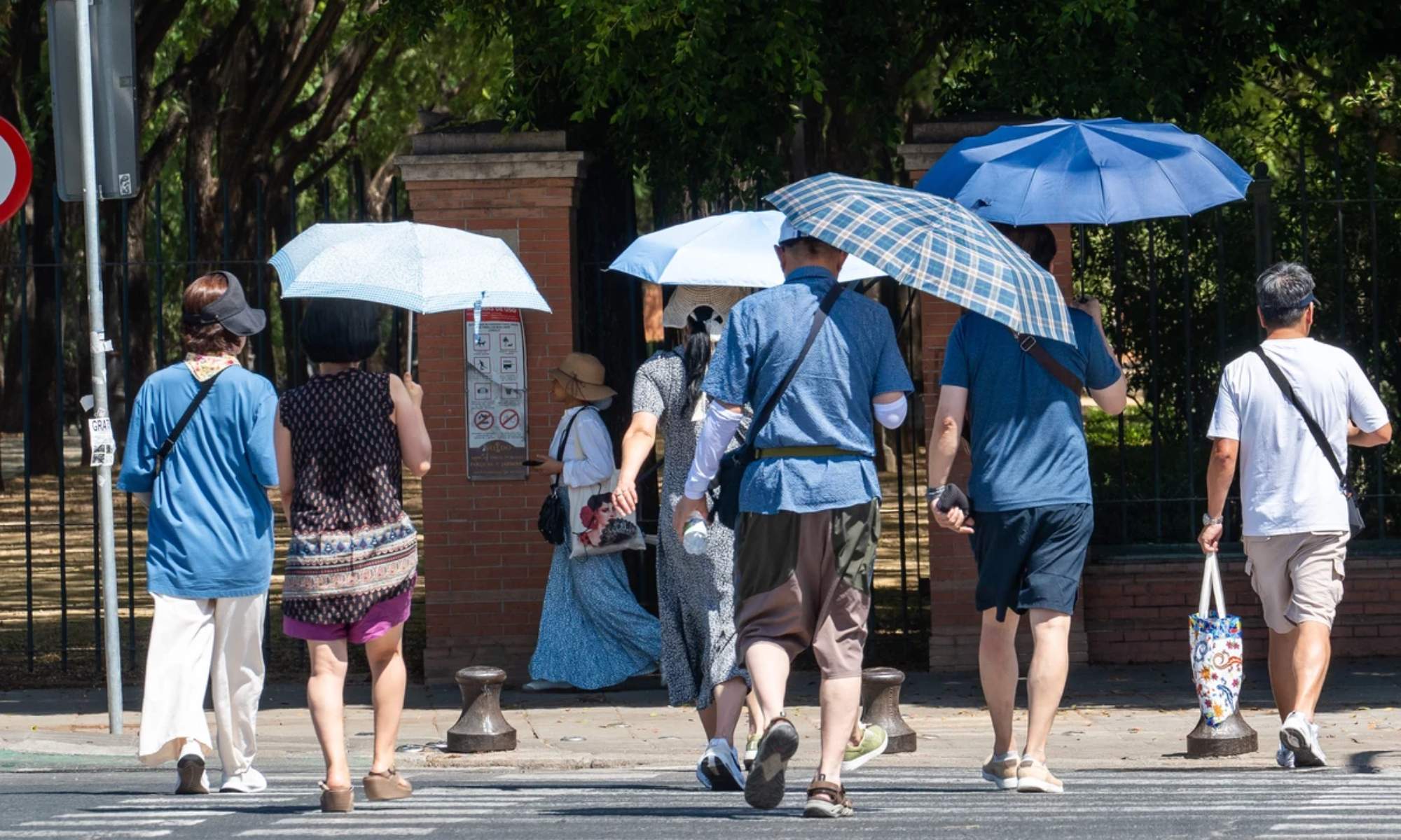 Varias personas con paraguas se protegen del intenso calor en Sevilla.