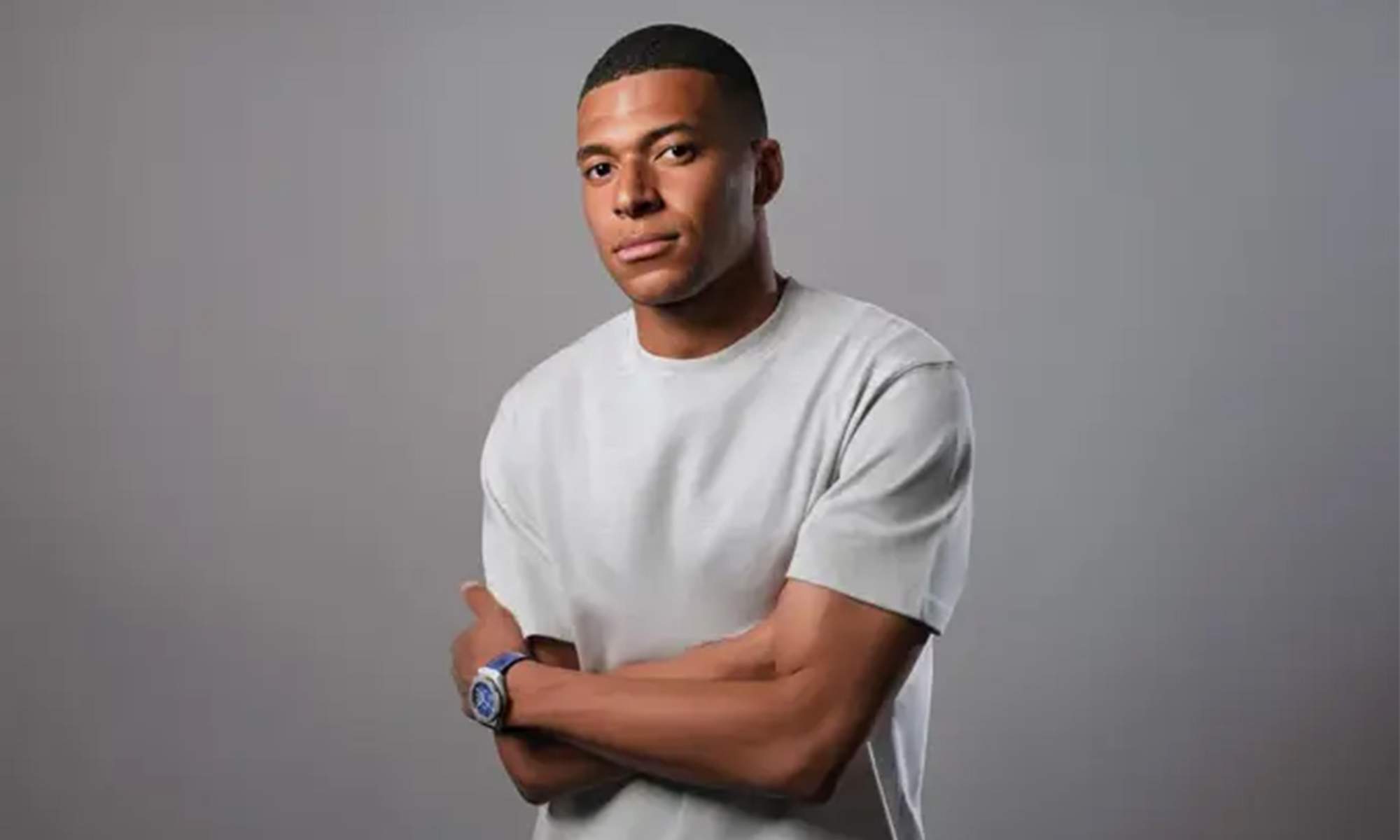 Mbappé con una camiseta blanca promocionando un reloj. 