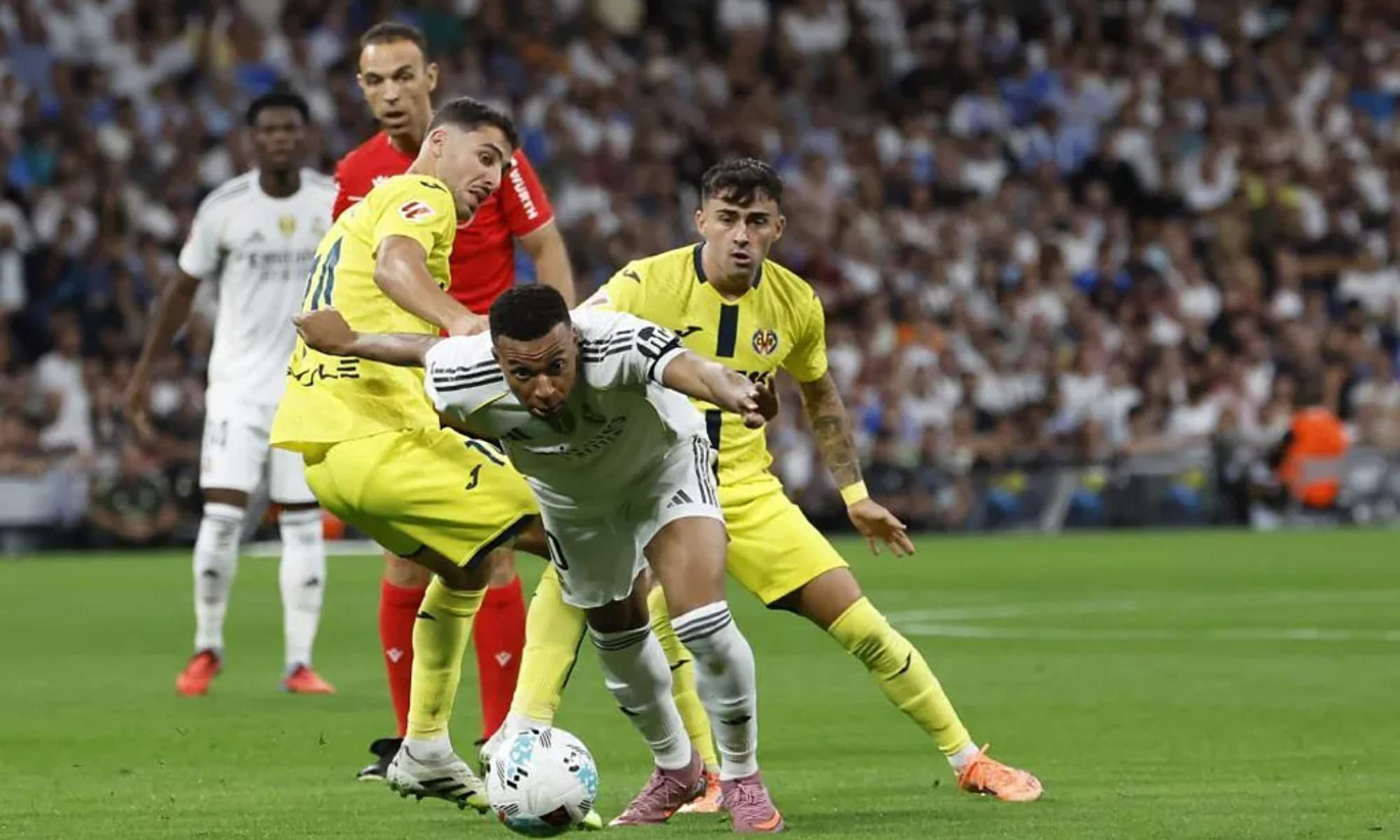 Kylian Mbappé, tratando de avanzar ante el marcaje de dos defensas del Villarreal, en el partido que esta noche ha ganado el Real Madrid.
