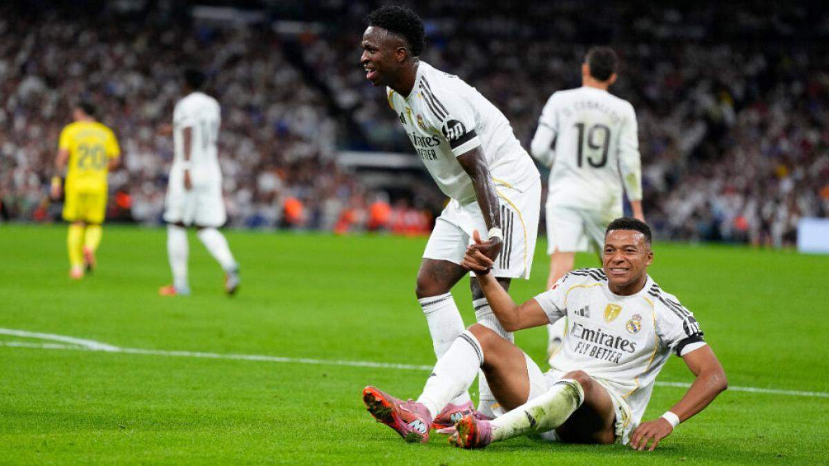 Vinícius Júnior levantando a Kylian Mbappé en un partido del Real Madrid.
