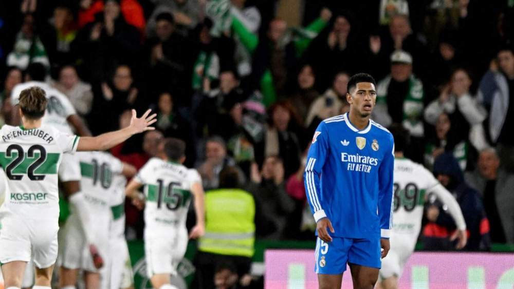 Jude Bellingham, serio, con los jugadores del Elche al fondo, que celebran el primer gol del partido del domingo contra el Real Madrid.