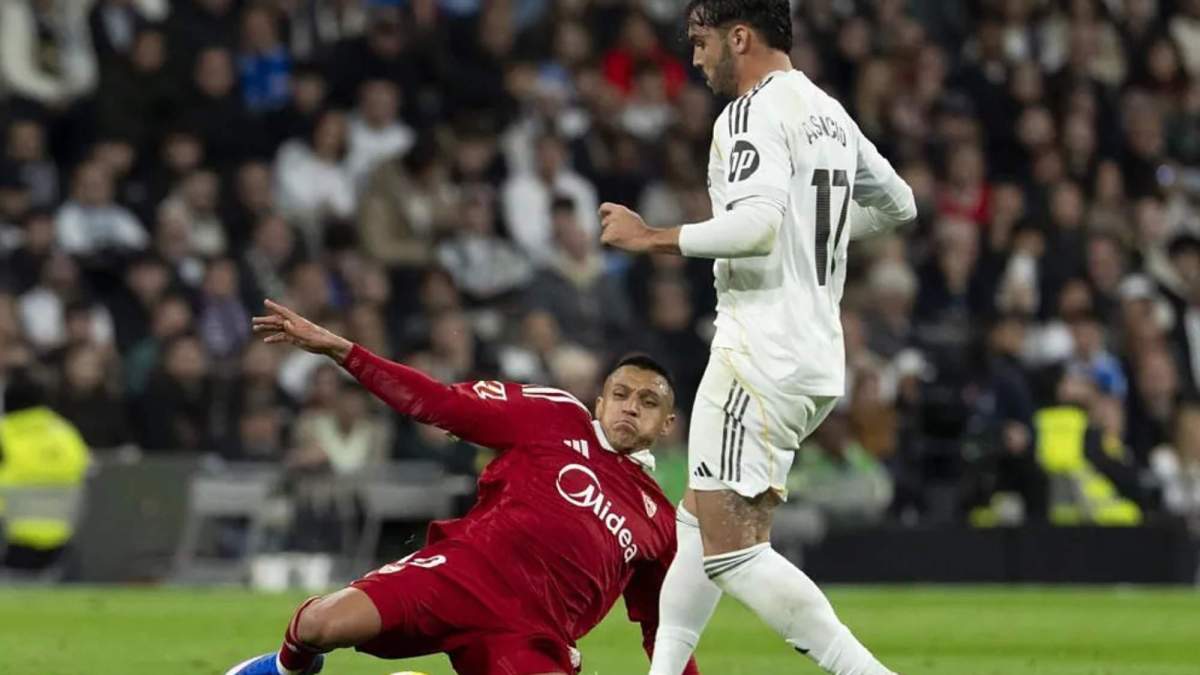 Alexis Sánchez, en el suelo, intenta cortar un pase de Raúl Asencio.