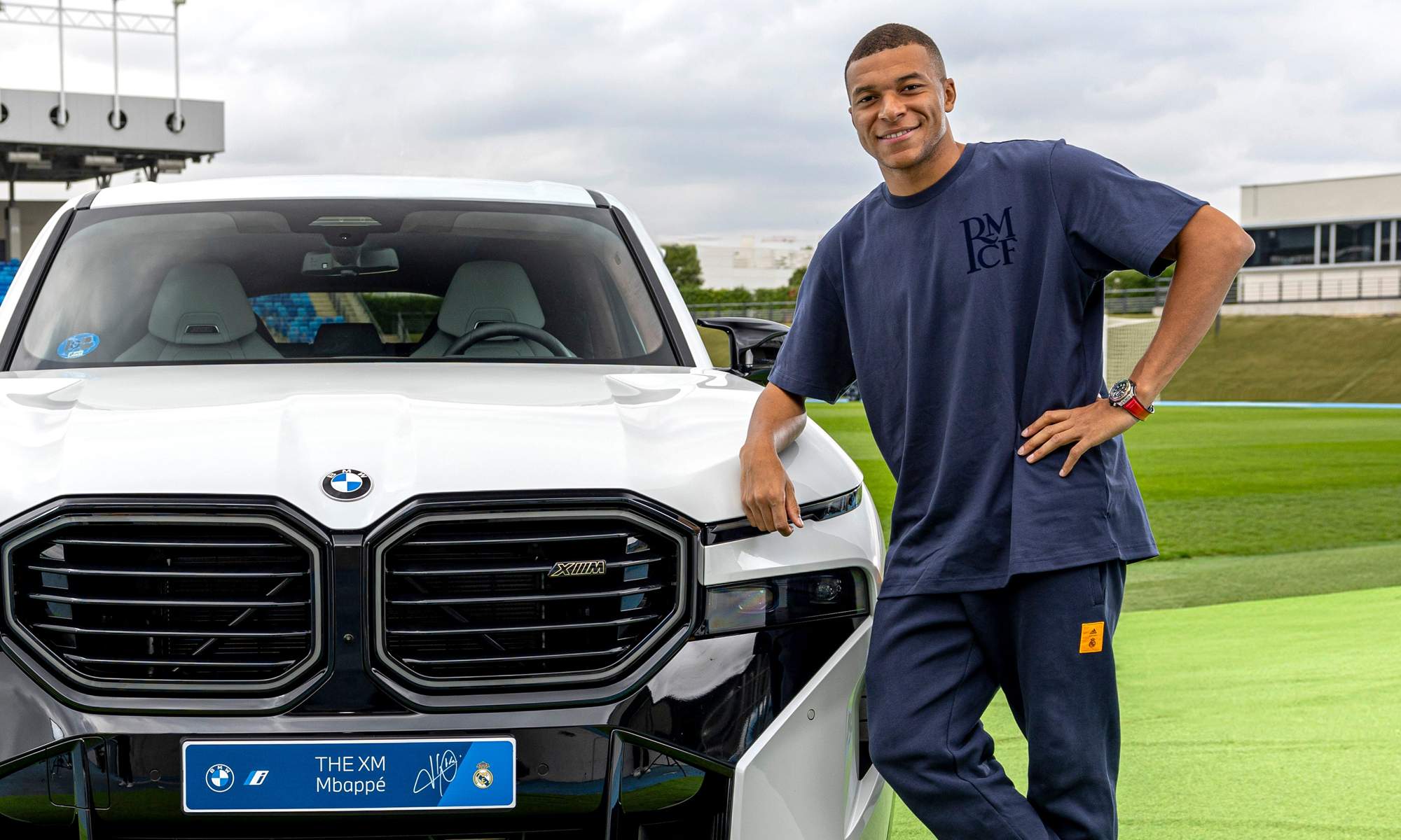 Kylian Mbappé posando con un coche. 