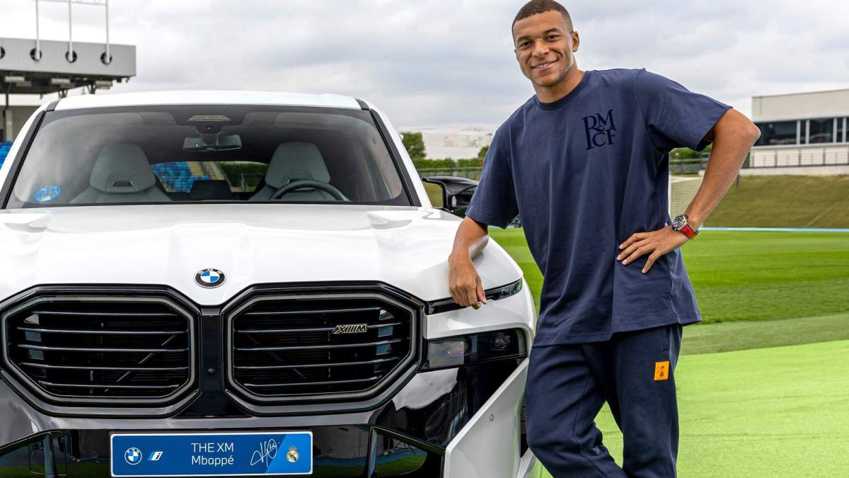Kylian Mbappé posando con un coche. 