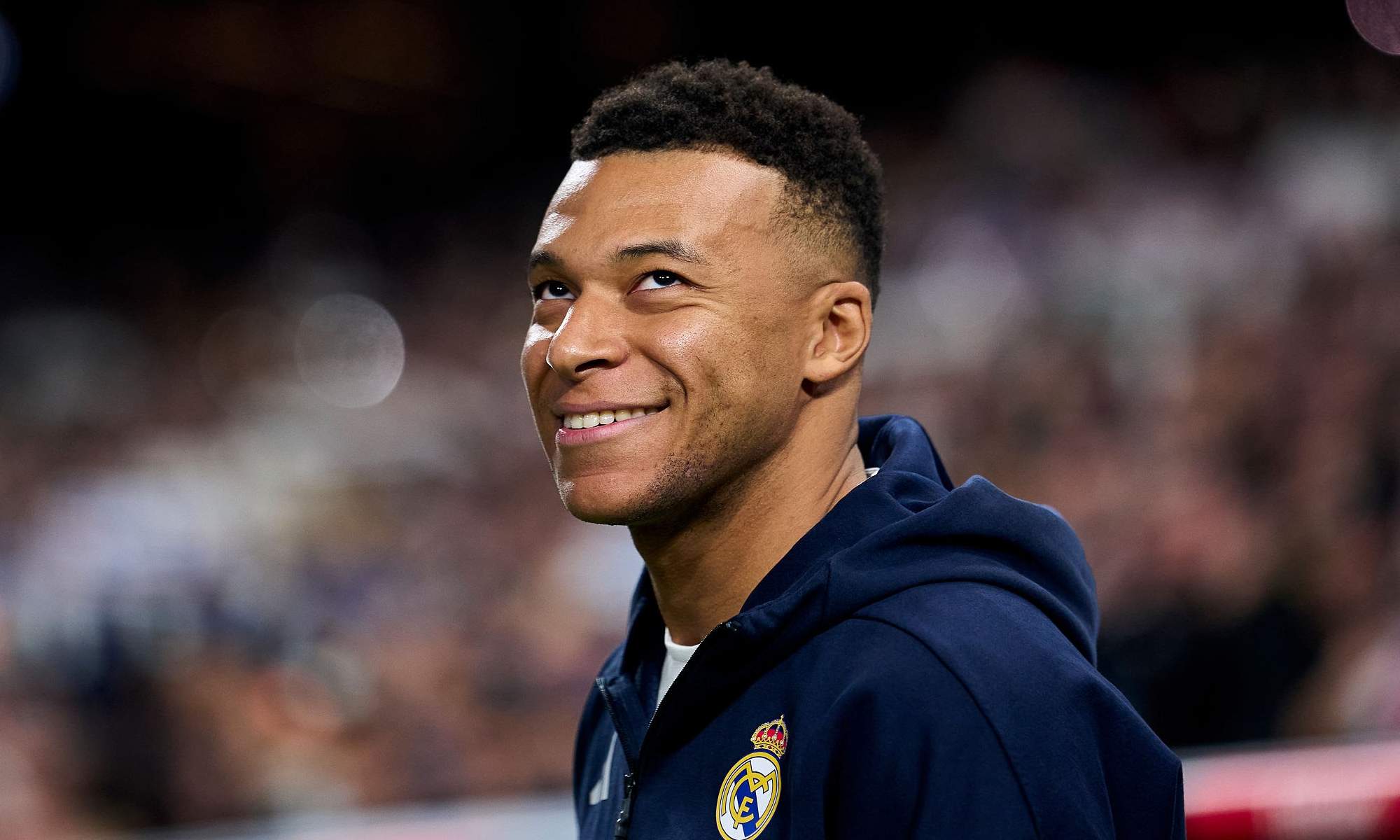 Kylian Mbappé sonriendo con la sudadera del Real Madrid. 