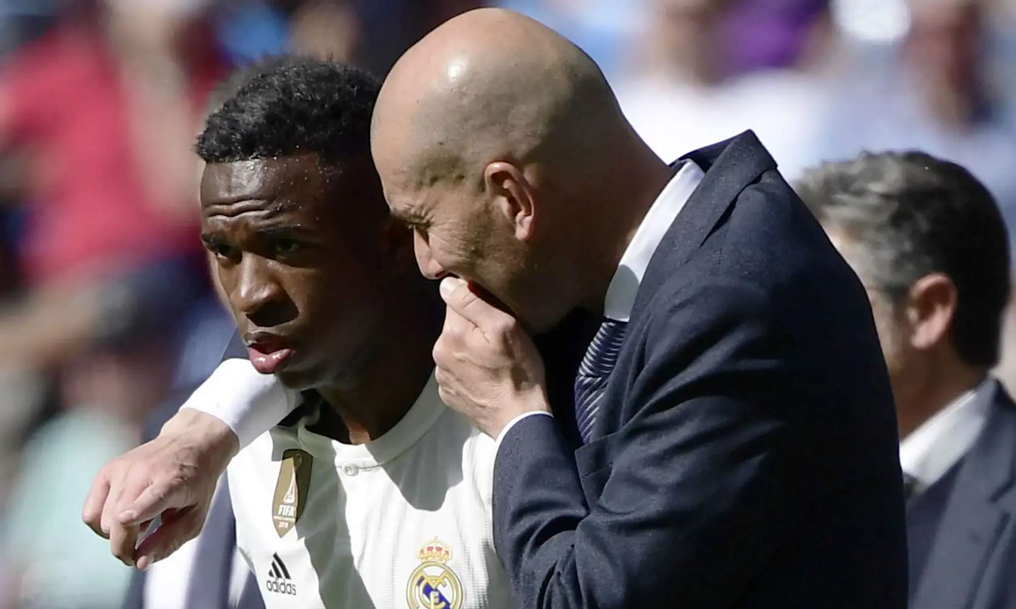 Zinedine Zidane hablando con Vinícius en un partido del Real Madrid.