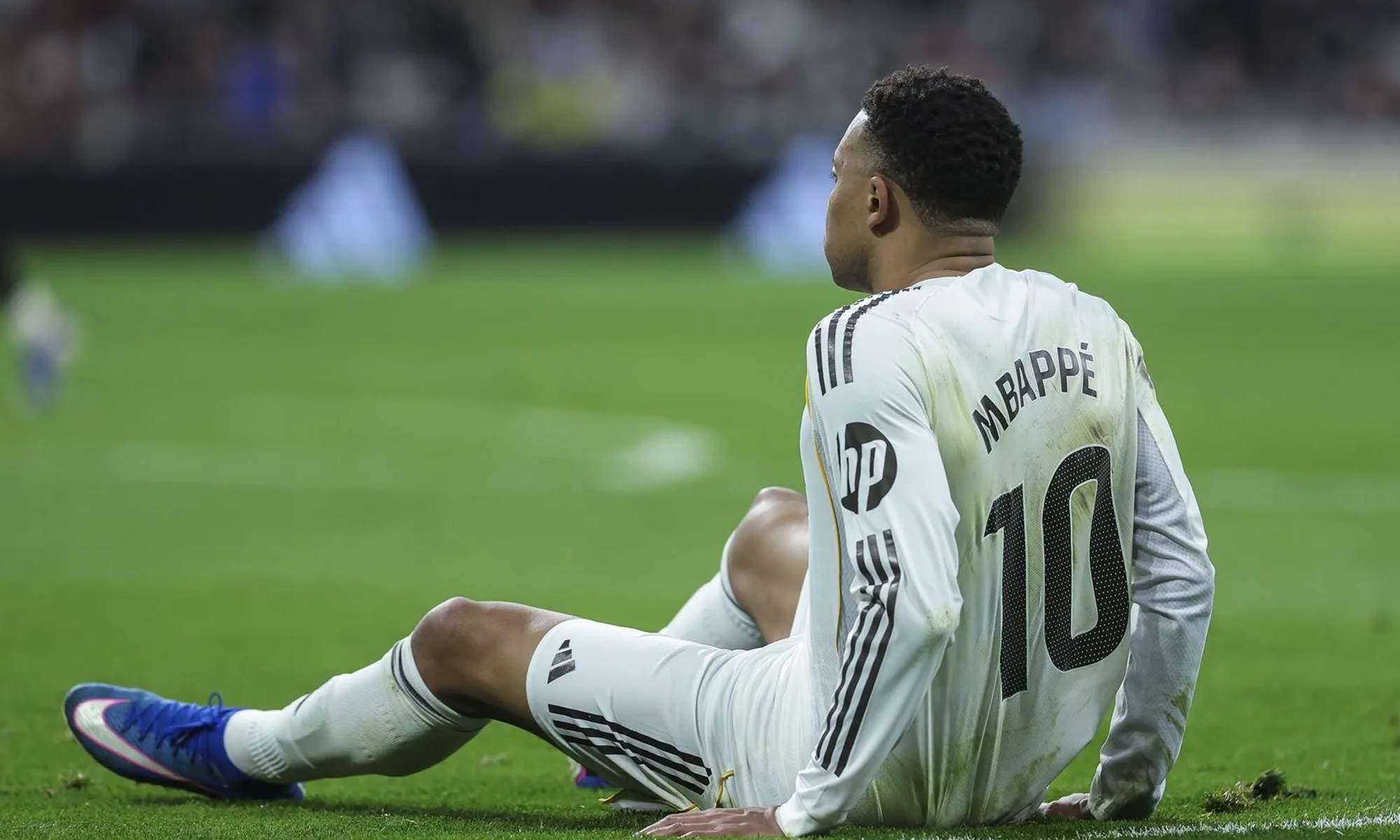 Kylian Mbappé sentado en el suelo en un partido.