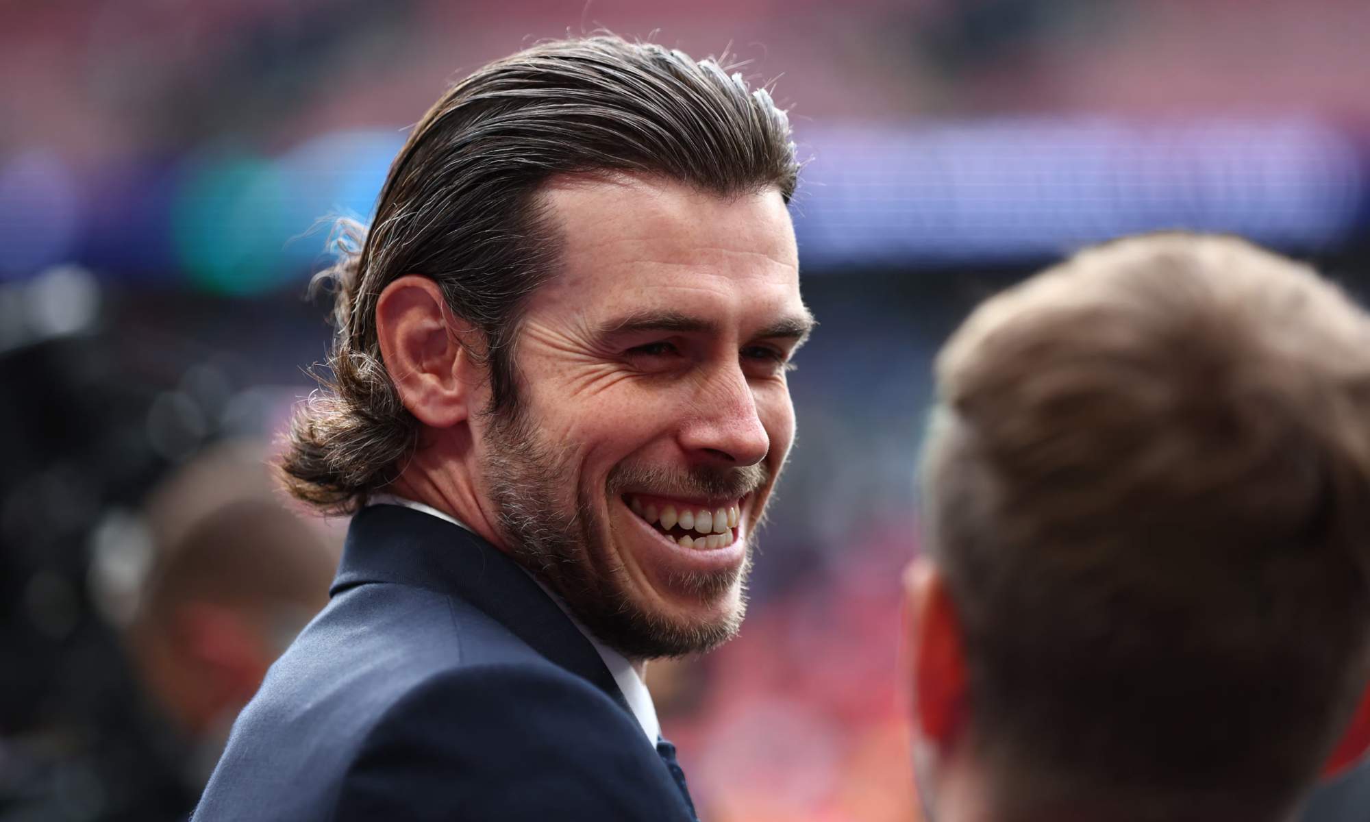 Gareth Bale, sonriendo, durante la retransmisión de un partido de fútbol que comentó.