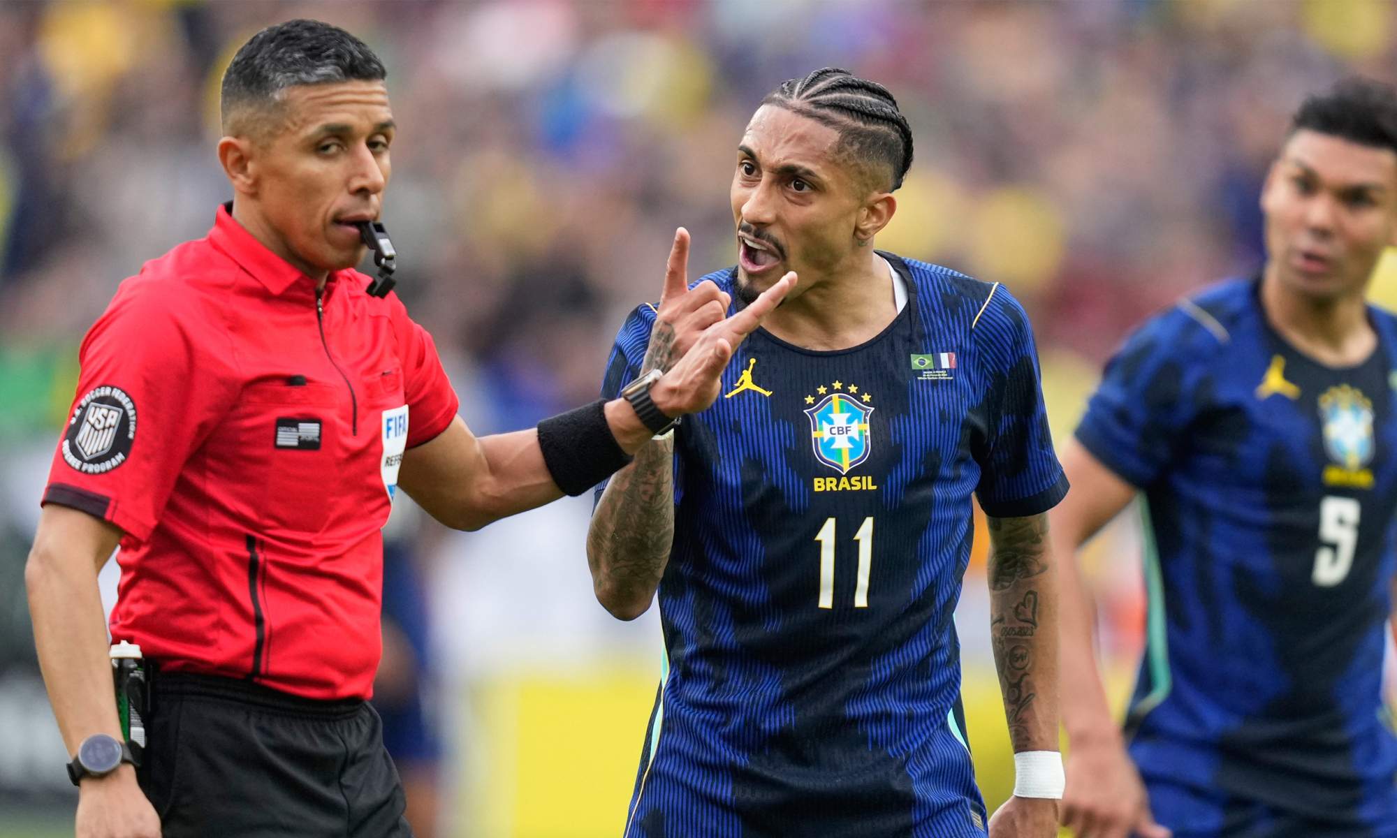 Raphinha protestando al árbitro en un partido de Brasil.