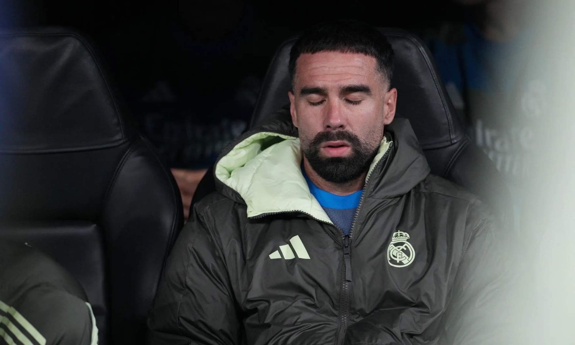 Dani Carvajal, sentado en el banquillo con los ojos cerrados y el rostro serio en un partido del Real Madrid durante esta temporada.