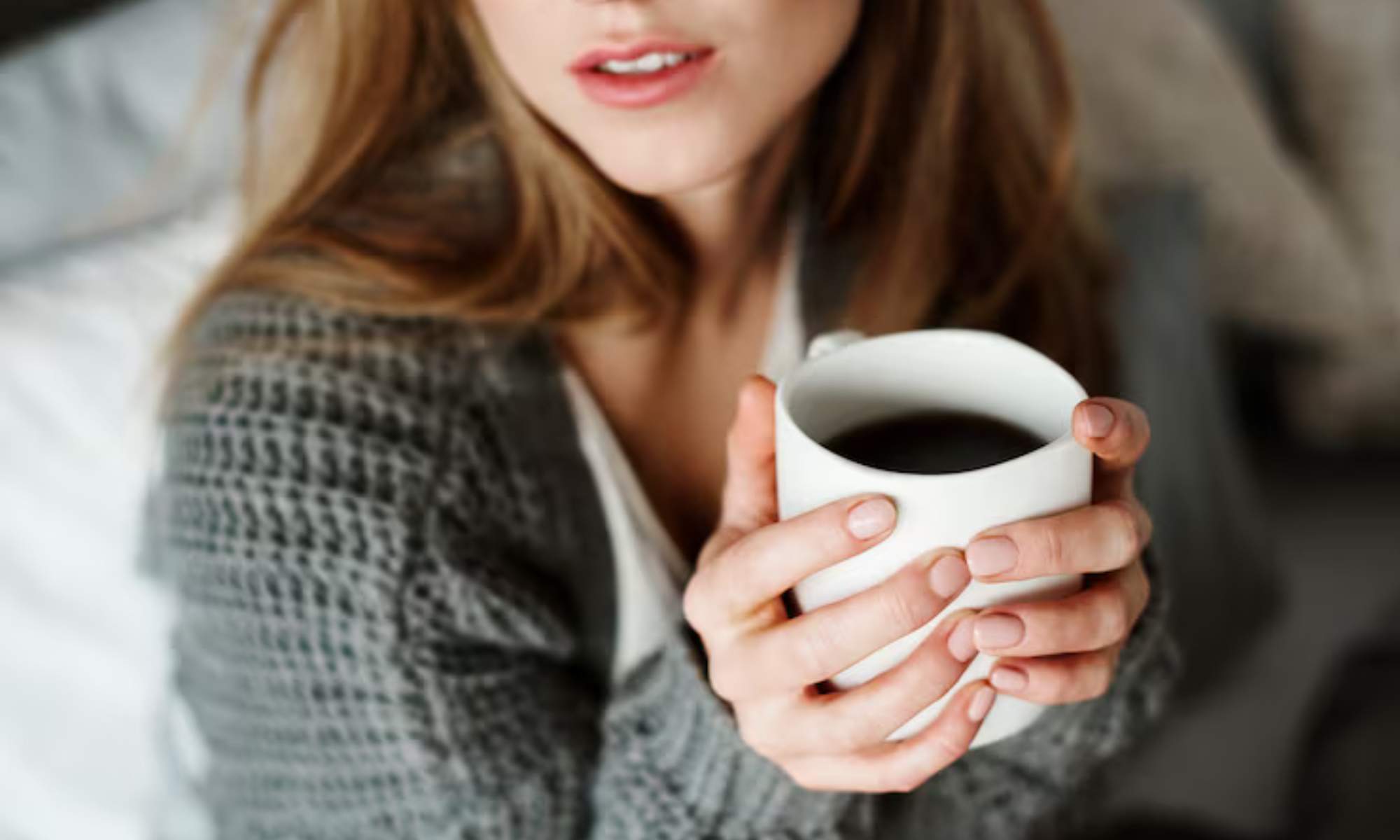 Una mujer, sosteniendo sobre sus manos una taza de café solo.
